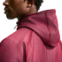 A profile view of a person wearing a burgundy mesh hoodie against a solid black background.