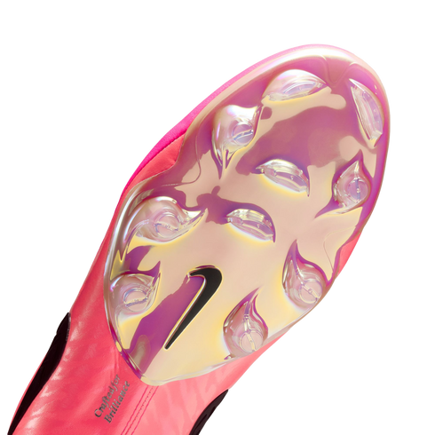 Bottom of a pink Nike soccer cleat featuring an iridescent soleplate, clear studs, a black Nike swoosh, and the text "Crafted for Brilliance" near the heel.