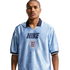 A man wearing a light blue, patterned Nike England football jersey with a navy blue collar and the Three Lions crest, posed against a white background.