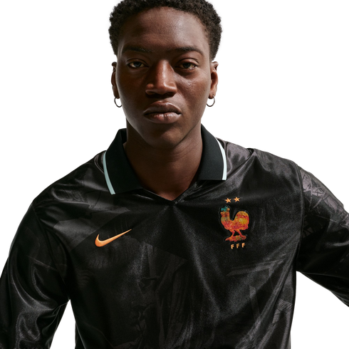 A man in a black long-sleeved Nike France jersey with a colorful rooster crest and two stars, set against a white background.