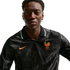 A man in a black long-sleeved Nike France jersey with a colorful rooster crest and two stars, set against a white background.
