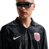 A man in sunglasses wears a black long-sleeved Nike Norway jersey featuring a grey celtic pattern, set against a white background.