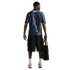 Rear view of a man wearing a blue star-patterned jersey with "STATES" on the back, black shorts, and silver sneakers, holding a black bag.
