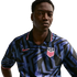 A man wearing a blue and black geometric pattern Nike USA soccer jersey with a USA crest, against a plain white background.