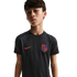 A young boy with short brown hair wearing a black Nike USA soccer jersey, looking at the camera against a solid black background.