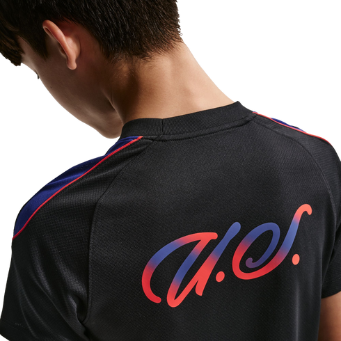 Close-up rear view of a person in a black jersey featuring a stylized red and blue gradient logo and shoulder stripes.