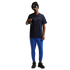 A full-body photo of a man standing against a solid black background. He is wearing a dark navy blue Nike t-shirt with "FRANCE" printed on the chest, bright blue athletic pants, black sneakers, a black Nike beanie, and blue-tinted sunglasses. He is holdin