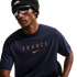 A person wearing a black Nike beanie and blue-framed sunglasses with a navy blue t-shirt featuring "FRANCE" and a rose-gold Nike logo.