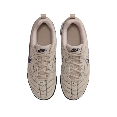 A top-down view of a pair of beige Nike sneakers on a black background, featuring suede and mesh panels, matching laces, and black branding details.