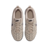 A top-down view of a pair of beige Nike sneakers on a black background, featuring suede and mesh panels, matching laces, and black branding details.