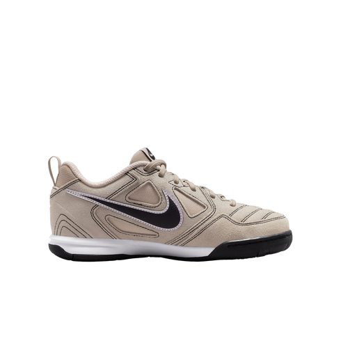 Side view of a tan Nike athletic sneaker featuring a black swoosh, white midsole, and black outsole against a solid black background.