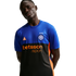 A man in a blue and black Inter Milan training jersey with orange "betsson.sport" and ACG logos. He poses with hands behind his back against a black background.