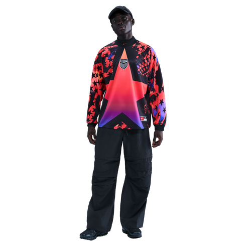 A person models a vibrant USA long-sleeve jersey with a large star design and baggy black pants against a black background.