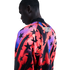 A man from the back wearing a vibrant jacket with black stars over red, orange, and purple gradients. The word "STATES" is printed on the upper back. Black background.