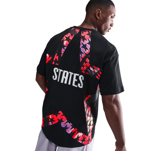 Rear view of a man wearing a black t-shirt with a large, colorful star-shaped graphic and the word "STATES" printed in bold white letters.