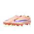 Peach-colored Nike soccer cleats with a large iridescent blue swoosh and orange studs, set against a black background.