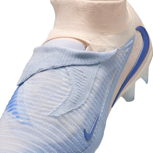 Close-up of a light blue and peach Nike soccer cleat with a textured, laceless knit upper and a sock-like collar against a black background.
