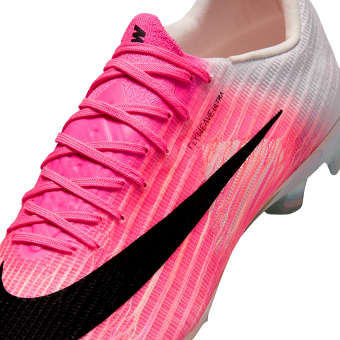 Close-up of a Nike Mercurial soccer cleat with a pink and white textured upper and a large black swoosh. The side features "FLYWEAVE ULTRA" text.