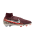 A high-top Nike soccer cleat is shown from a side profile against a solid black background. The shoe features a burgundy ribbed upper and a matching sock-like ankle collar. A large, metallic silver Nike swoosh with an orange border sits on the side, print
