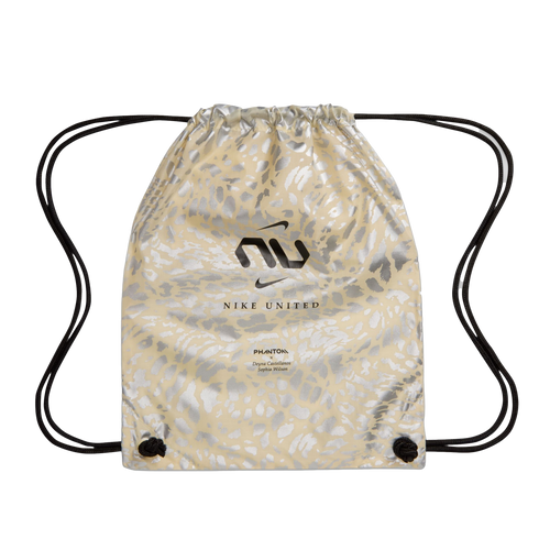 A beige drawstring bag with a metallic silver animal print pattern. The front features a black "NU" graphic with a Nike swoosh, the words "NIKE UNITED," and smaller text referencing "PHANTOM," Deyna Castellanos, and Sophia Wilson.