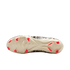 A bottom-up view of a cream-colored soccer cleat with bright orange studs and a black-and-white patterned upper against a solid black background.
