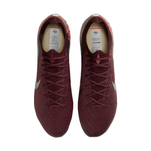 A top-down view of a pair of maroon Nike soccer cleats with a textured, knitted upper against a solid black background.