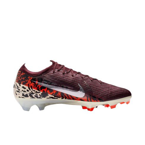 A side-profile studio shot of a Nike Mercurial soccer cleat against a solid black background. The shoe features a deep maroon ribbed upper and a large white Nike swoosh. The lower half of the boot is adorned with a bold graphic pattern in orange, black, a