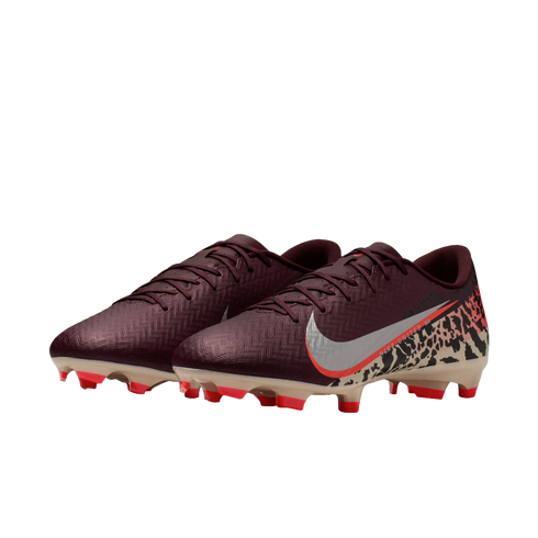 A pair of burgundy Nike soccer cleats against a black background. The right shoe displays a silver Nike swoosh with an orange border and a beige leopard print pattern on the heel. The sole is tan with vibrant orange studs.