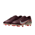 A pair of burgundy Nike soccer cleats against a black background. The right shoe displays a silver Nike swoosh with an orange border and a beige leopard print pattern on the heel. The sole is tan with vibrant orange studs.