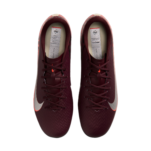 A top-down view of a pair of burgundy Nike Mercurial soccer cleats with silver Nike swooshes and orange accents, set against a black background.