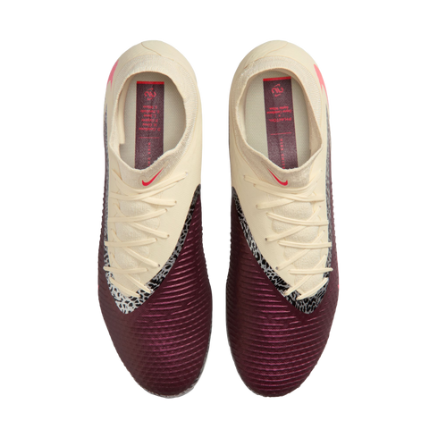 Top-down view of cream and maroon Nike soccer cleats with a textured surface and black-and-white accents, set against a black background.