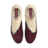Top-down view of cream and maroon Nike soccer cleats with a textured surface and black-and-white accents, set against a black background.