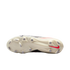 Underneath view of a Nike soccer cleat featuring a cream soleplate with grey studs, a red Nike swoosh, and a patterned upper against a black background.