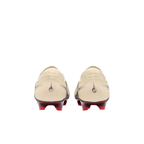 A rear view of a pair of cream-colored soccer cleats with maroon heel plates and bright red studs, set against a solid black background.