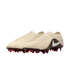 A pair of cream-colored Nike soccer cleats with a textured upper, animal-print heel, silver swoosh logo, and dark red studs against a black background.