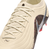 A close-up shot of a cream-colored Nike soccer cleat with a textured ribbed upper and matching laces. A metallic silver swoosh sits atop a dark brown mottled pattern on the side. The background is solid black.