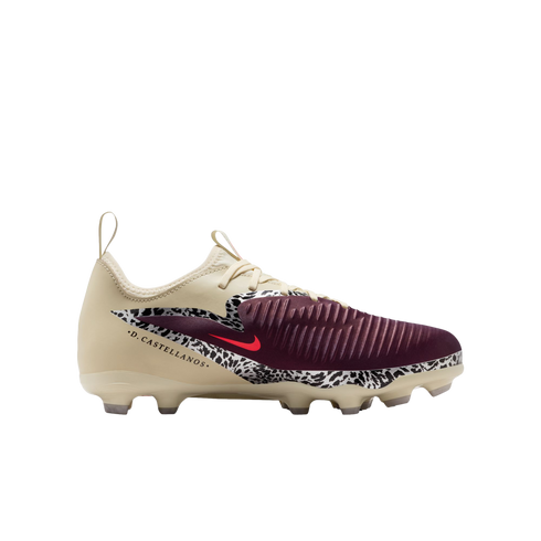 A profile view of a Nike soccer cleat against a solid black background. The shoe features a cream-colored upper, a maroon ribbed toe, and a black-and-white speckled pattern across the mid-section with a small red Nike swoosh. The name ".D. CASTELLANOS." i