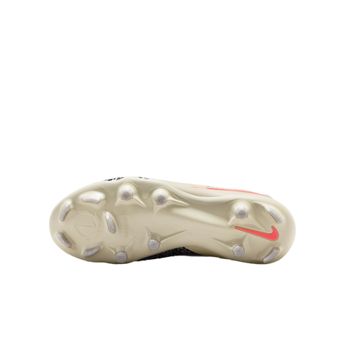 The cream-colored soleplate of a Nike football boot featuring a coral swoosh and various studs, centered against a black background.