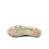 The cream-colored soleplate of a Nike football boot featuring a coral swoosh and various studs, centered against a black background.