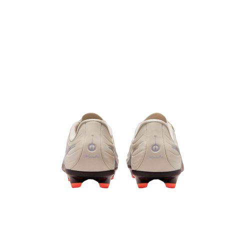 A rear view of a pair of off-white soccer cleats against a black background, featuring black soleplates with bright orange studs and "Maestro" scripted on each heel.