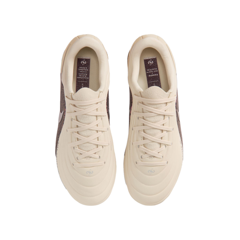 A top-down view of a pair of cream-colored Nike Tiempo soccer cleats centered against a black background. The shoes feature matching cream laces and a quilted, textured upper. Inside each shoe, a dark purple insole displays the "Tiempo" name and a list of
