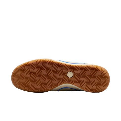 A view of the gum rubber outsole of a shoe against a black background, featuring an intricate herringbone tread pattern and a white hexagonal Nike logo in the center.