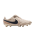 A side profile view of a tan leather Nike soccer cleat against a solid black background, featuring a dark navy blue swoosh and colorful stitching near the heel.