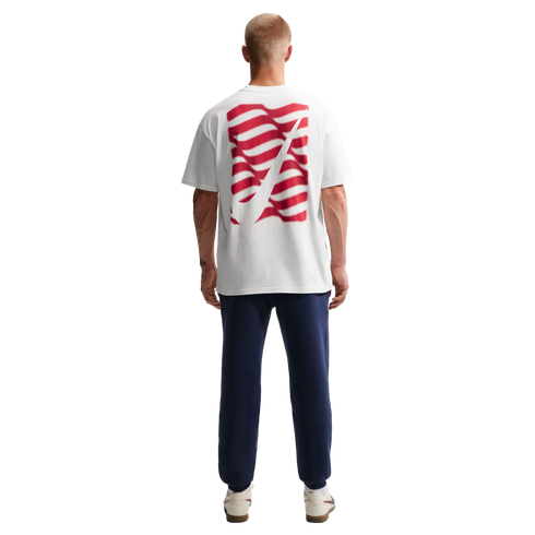 Rear view of a man wearing a white t-shirt with a red wavy graphic, navy blue sweatpants, and white sneakers against a solid black background.
