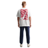 Rear view of a man wearing a white t-shirt with a red wavy graphic, navy blue sweatpants, and white sneakers against a solid black background.
