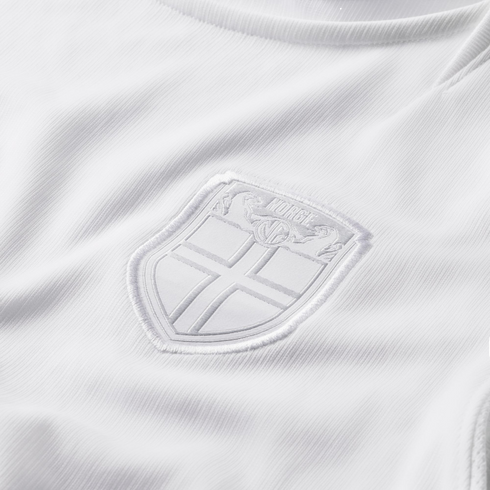 Close-up of a white textured jersey with a tonal, white-on-white embroidered crest. The shield-shaped badge features a cross and the word "NORGE" at the top.