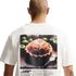 A back view of a person with a shaved head wearing a white t-shirt against a black background. The shirt features a large graphic on the back resembling a vintage magazine advertisement. The main image shows a baked pie with a soccer-ball-patterned crust