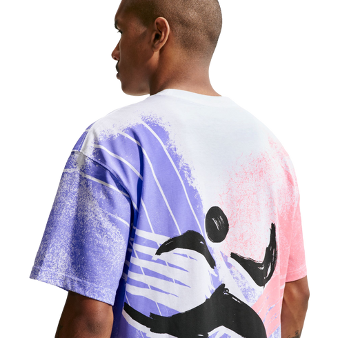 A back view of a person wearing a white t-shirt with a large, abstract graphic. The design features textured purple and pink washes with a dynamic black brushstroke figure in the center.