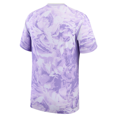 Back view of a short-sleeved athletic shirt with a large-scale lavender tonal floral print and subtle lime green trim along the shoulder seams.