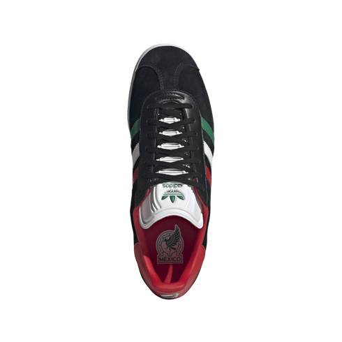 Overhead view of a black Adidas sneaker with green, white, and red stripes, a red interior, and a Mexico logo on the insole, set against a black background.